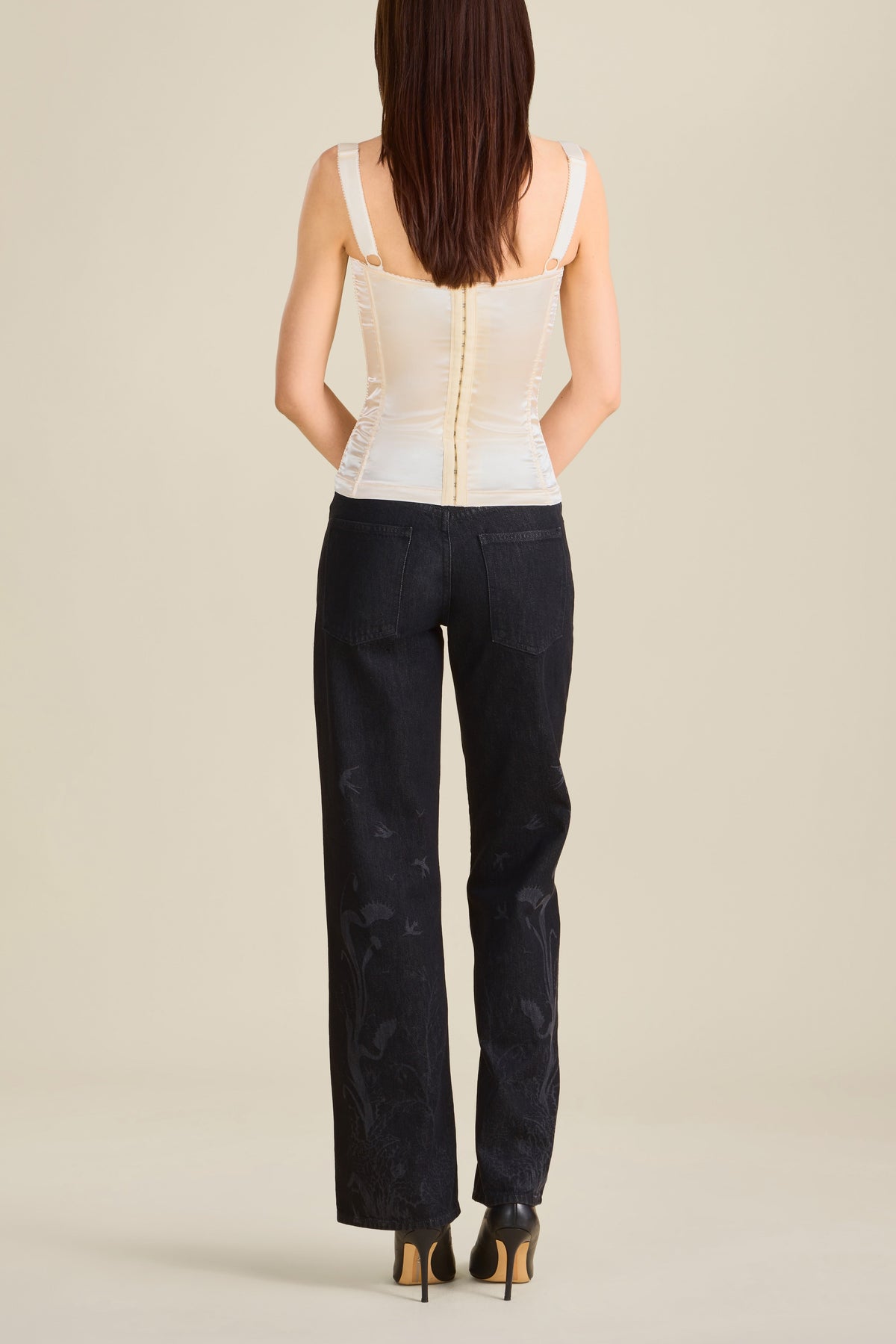 Woman wearing a beige top and black pants on a beige background